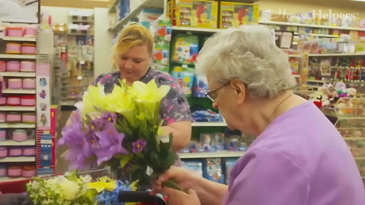 Caregiver and senior at a store holding a bouquet as a hobby part of social wellness