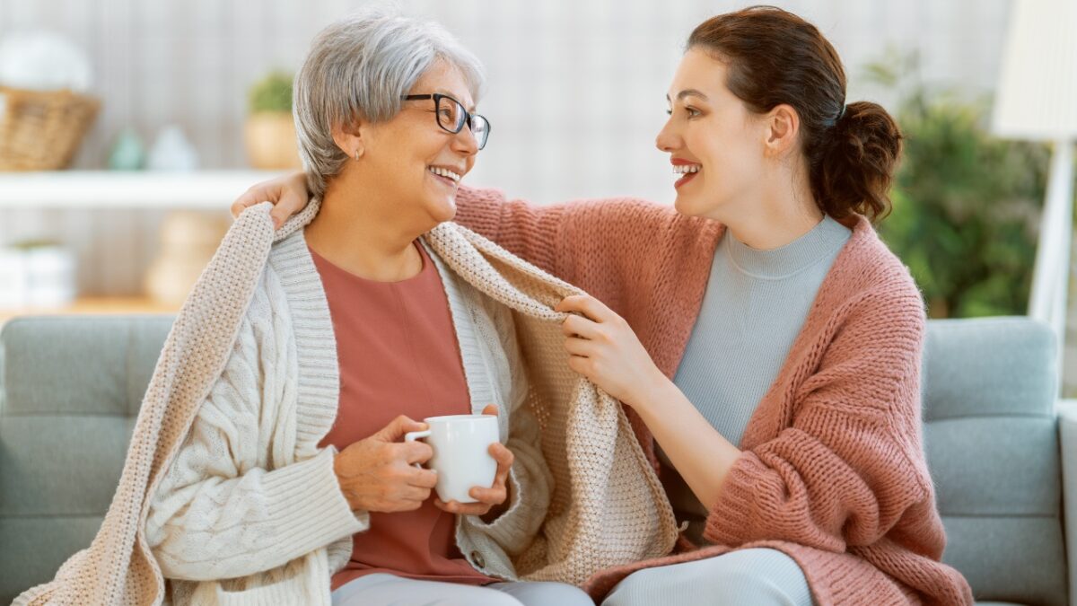 Caregiver placing a warm blanket over senior's shoulder as winter wellness for seniors in Manatee County.