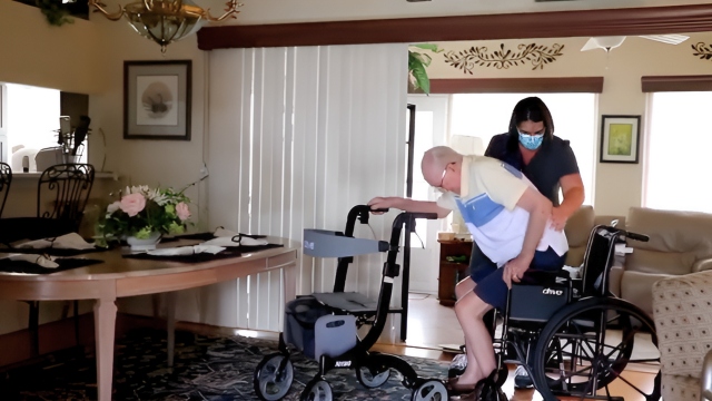 Caregiver helping senior transfer from walker to wheelchair