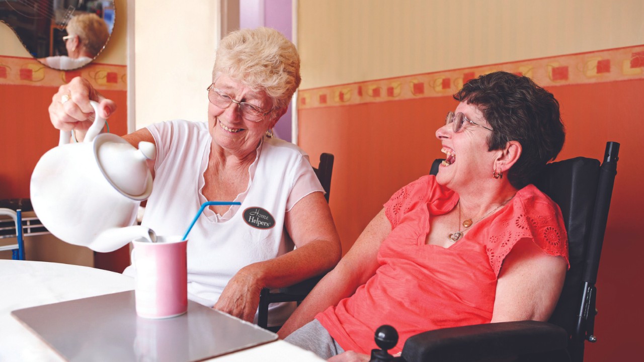 Caregiver serving water to senior client for in-home care services.