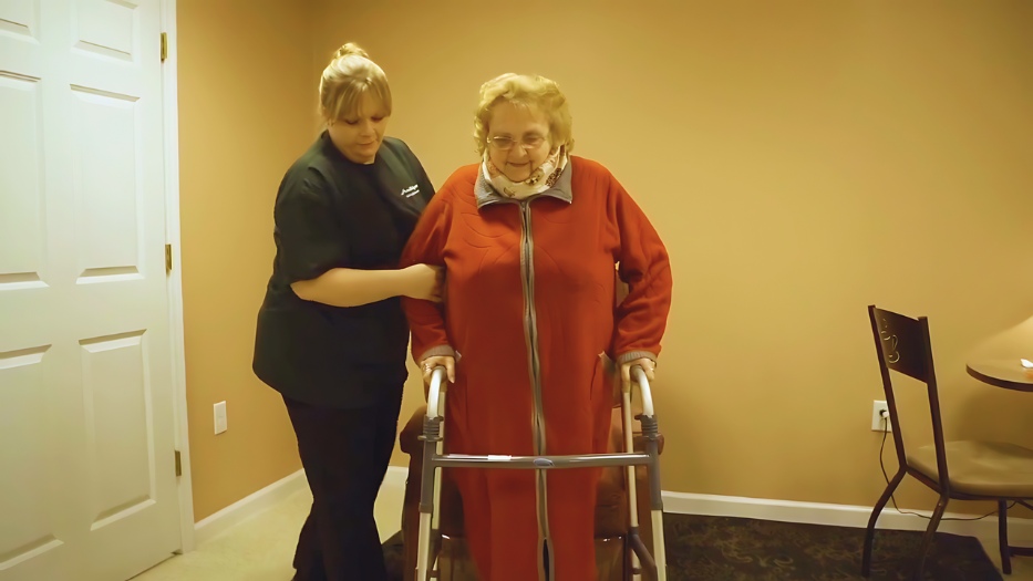 Home Helpers home health aide assisting senior woman client in walking using the walker.