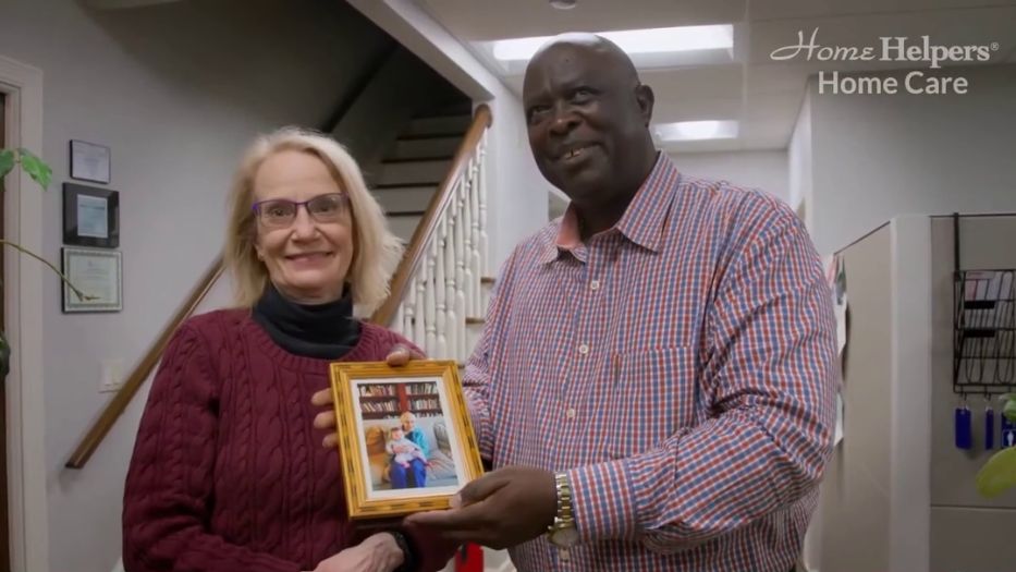 Home Helpers male caregiver giving a framed photo, a perfect gift for senior this holiday season Customized Photo Gift for Seniors This Holiday Season