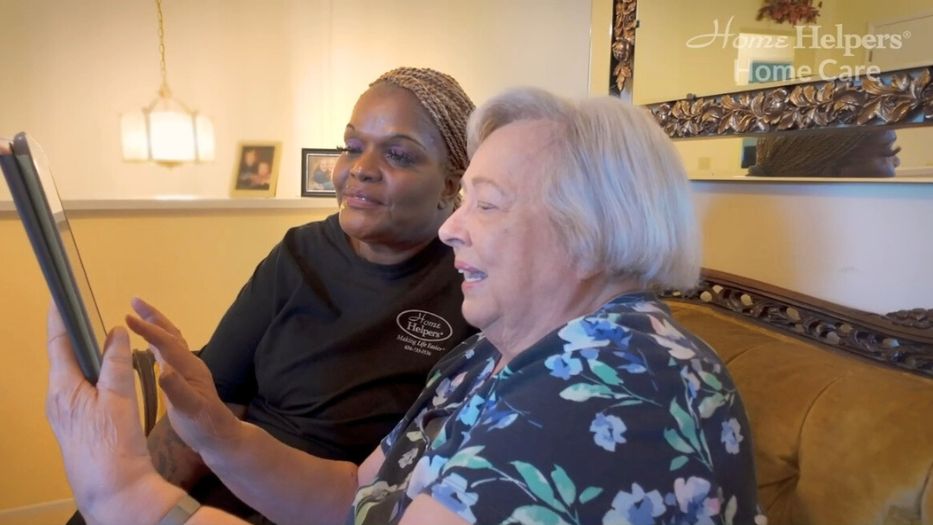 Senior woman holding a tablet with her caregiver by her side.