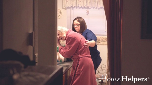 Caregiver assisting senior female in the bathroom washing her hair.