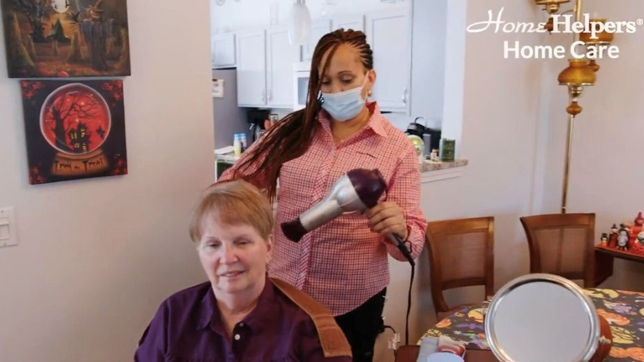 Caregiver is blow-drying another person's hair.