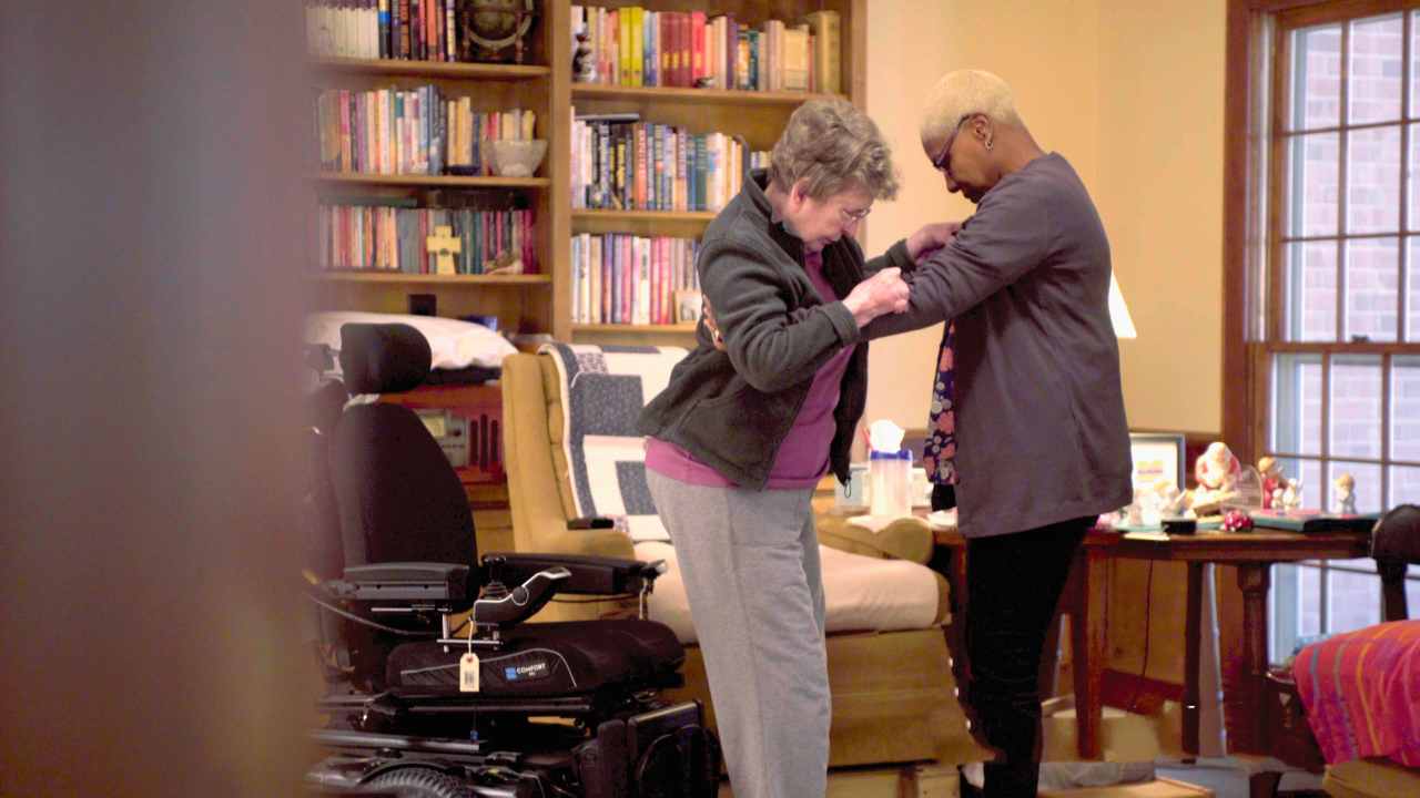 Caregiver assisting senior in standing to prevent fall.