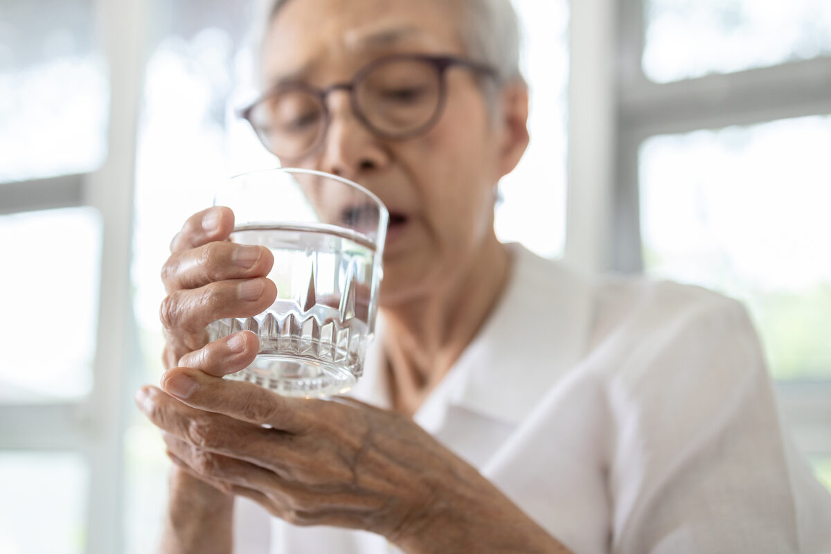 Senior Woman Holding Glass Of Water,hand Shaking While Drinking