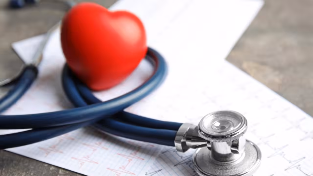 A stethoscope and a red heart-shaped object rest on printed electrocardiogram (ECG) charts, symbolizing heart conditions in seniors and emphasizing the importance of medical care for aging hearts.