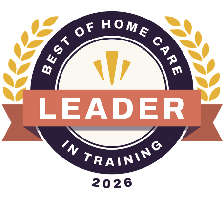 A circular badge with gold laurel leaves and the text “Best of Home Care Leader in Training 2026.” A rust-colored ribbon with the word “Leader” is across the center.