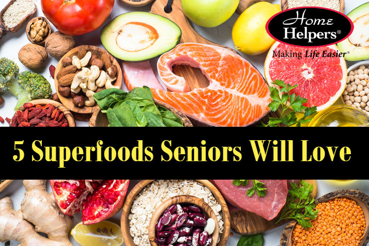 A colorful assortment of healthy foods like salmon, nuts, seeds, leafy greens, and fruits, with a banner that reads, 5 Superfoods Seniors Will Love. The Home Helpers logo is in the top right corner.
