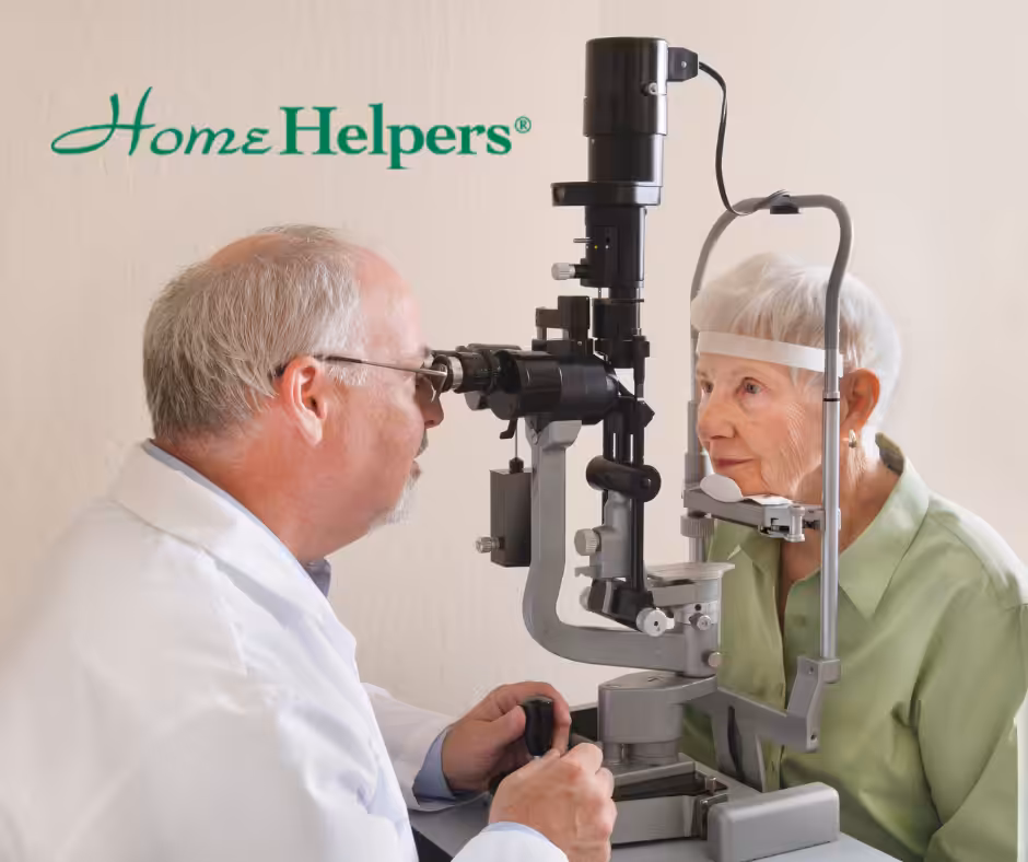 An eye doctor examines an elderly woman’s eyes using a slit lamp in a clinical setting. The woman is seated and looking into the machine. The Home Helpers logo appears in the top left corner.