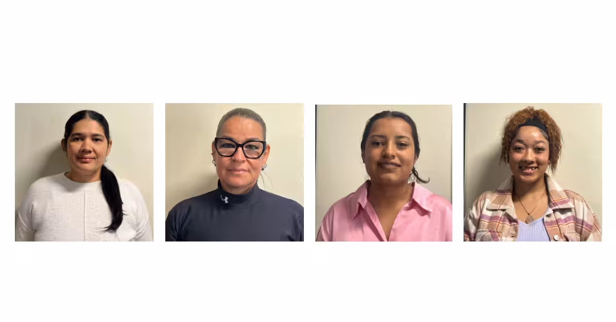 Four women are shown in separate portrait photos, each smiling, standing against a plain light-colored wall. They wear different outfits including a white top, a dark turtleneck, a pink shirt, and a plaid jacket.