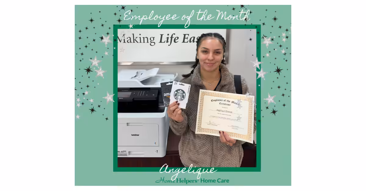 A woman stands indoors holding a Starbucks gift card and a certificate. The image has a green border with stars and text reading Employee of the Month, Angelique, and Home Helpers Home Care.