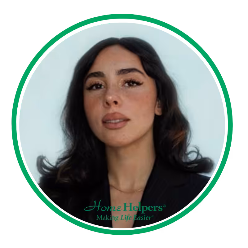 Portrait of a woman with long dark hair, wearing a black top, looking slightly upward. The image is framed by a green circle with the Home Helpers logo and the tagline Making Life Easier at the bottom.