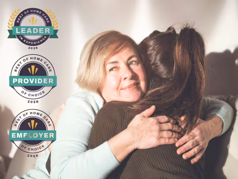 An older woman with short blond hair happily hugs a younger woman. To the left, there are three award badges reading “Leader,” “Provider,” and “Employer” for “Best of Home Care” in 2020.