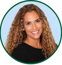 Smiling woman with long curly hair, wearing a black top, posed in front of a light blue background inside a green circular frame.
