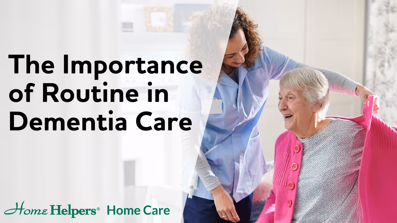 A caregiver helps an elderly woman put on a pink cardigan; both are smiling. The text reads, The Importance of Routine in Dementia Care. The Home Helpers Home Care logo is at the bottom.