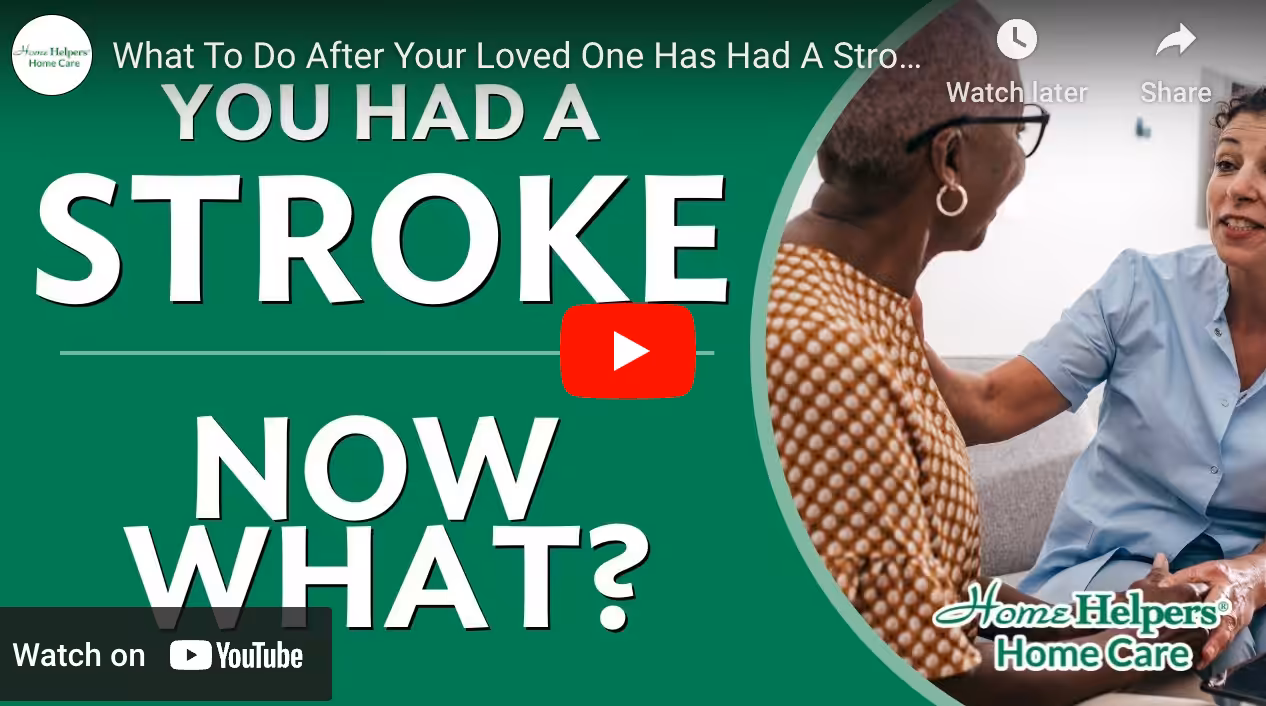 Screenshot of a YouTube video titled What To Do After Your Loved One Has Had A Stroke. The text on screen says You had a stroke, now what? Two women, one comforting the other, sit on a couch. Home Helpers Home Care logo is visible.