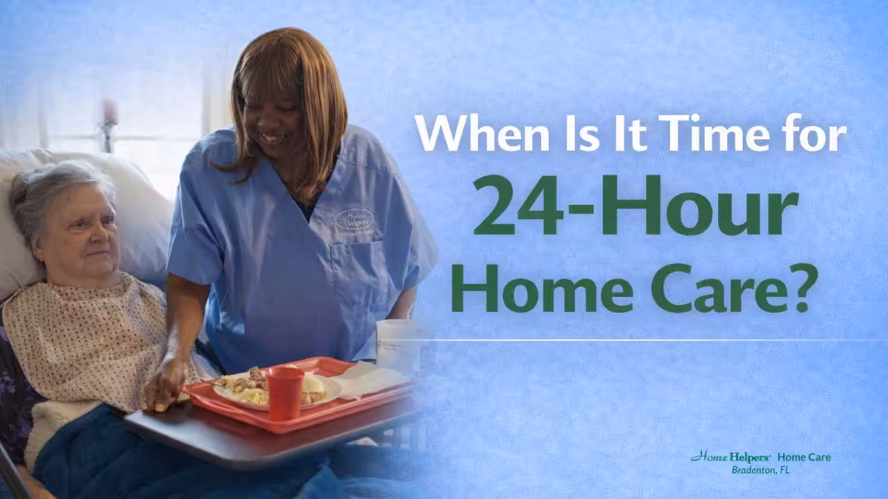 A nurse in blue scrubs smiles while handing a meal tray to an elderly woman in bed. Text reads, When Is It Time for 24-Hour Home Care? The setting suggests a calm, caring home environment.