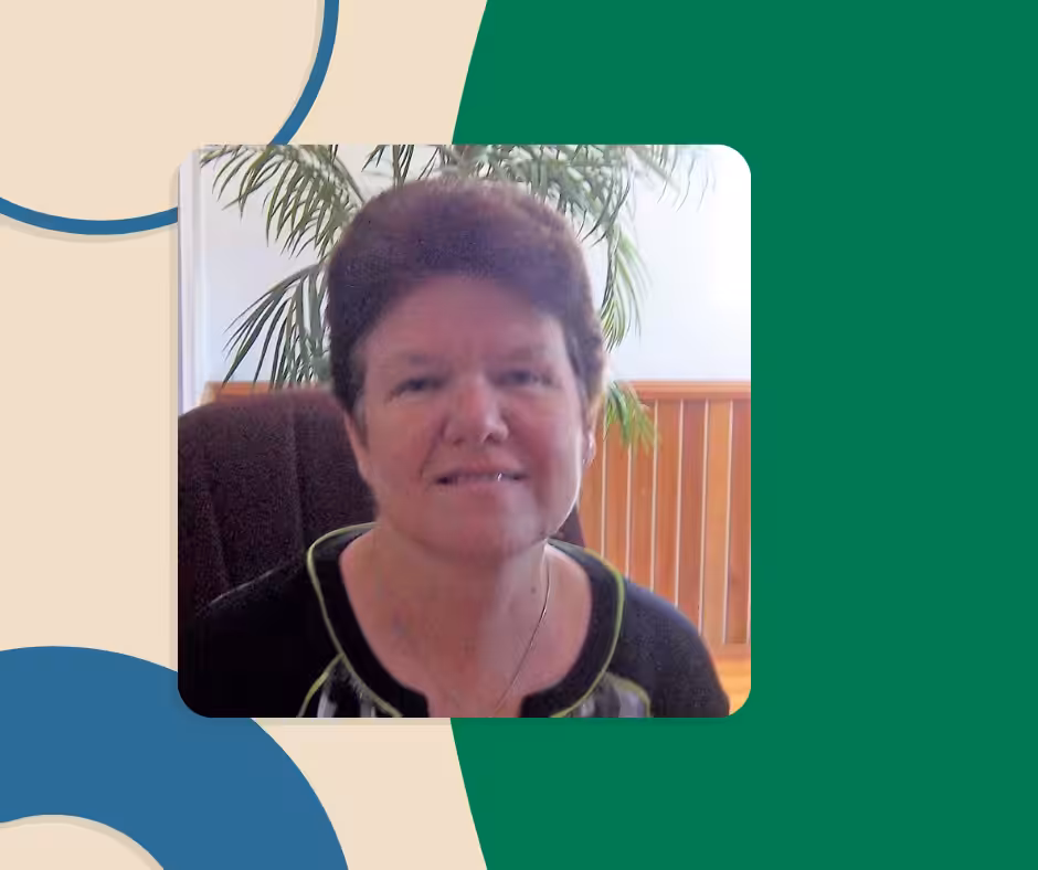 A woman with short brown hair sits indoors in front of a wooden railing and a leafy green plant, smiling at the camera. The image is framed by a graphic design with beige, green, and blue curved shapes.