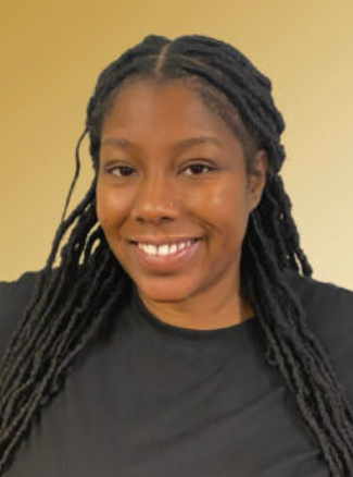 A woman with long, dark braided hair smiles at the camera. She is wearing a black top and is in front of a plain light yellow background.