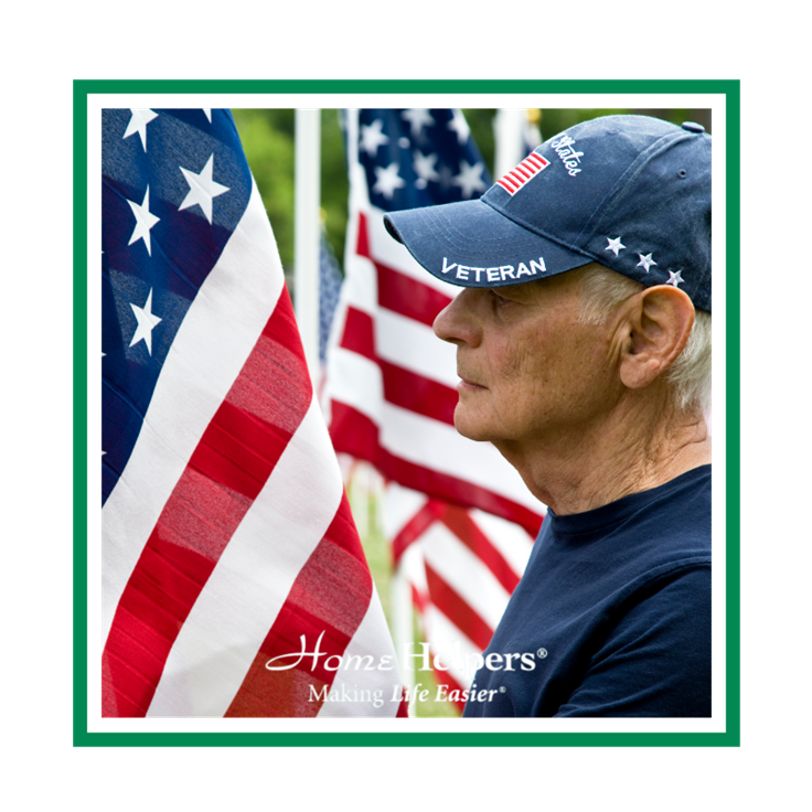 An elderly man wearing a Veteran cap stands in profile beside several American flags. The image includes the Home Helpers logo and the slogan Making Life Easier at the bottom.