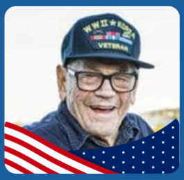 Smiling elderly man wearing glasses and a WWII Korea Veteran hat; image is framed with an American flag design at the bottom.