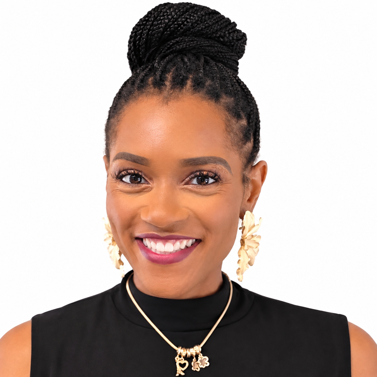 A smiling woman wearing a black high-neck top, gold drop earrings, and a gold charm necklace.