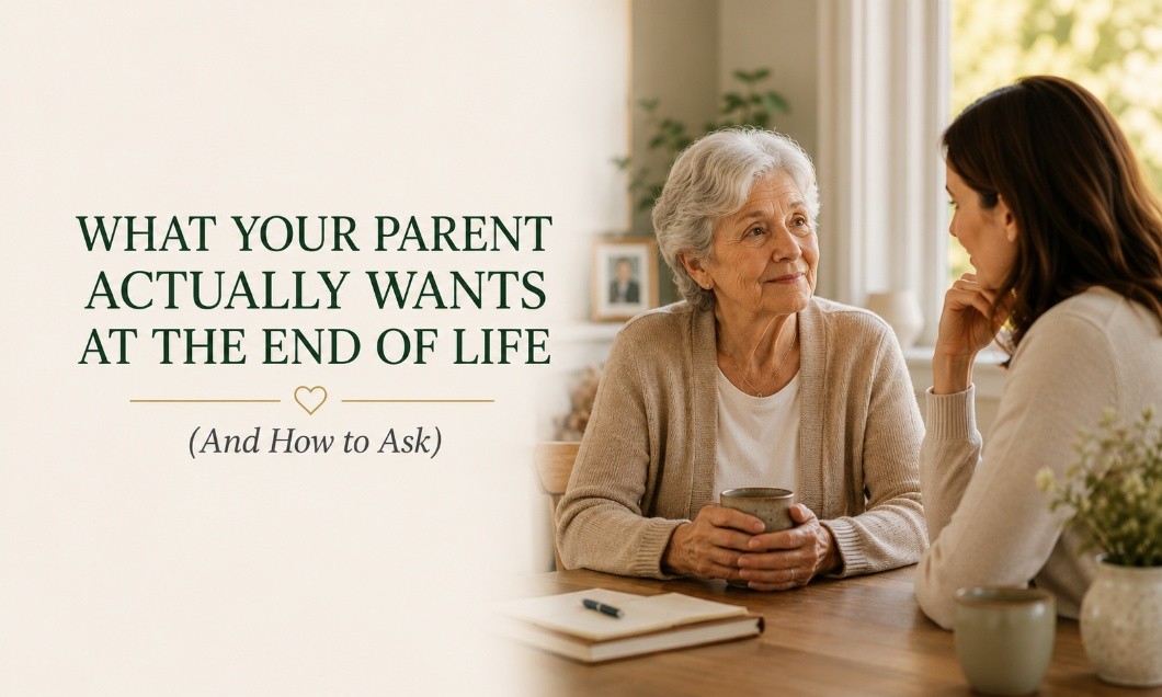 Two women sit at a table with mugs, having a serious conversation. Text reads, What your parent actually wants at the end of life (and how to ask). A notebook and plant are on the table.