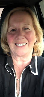 A smiling woman with blonde hair sitting in a car.