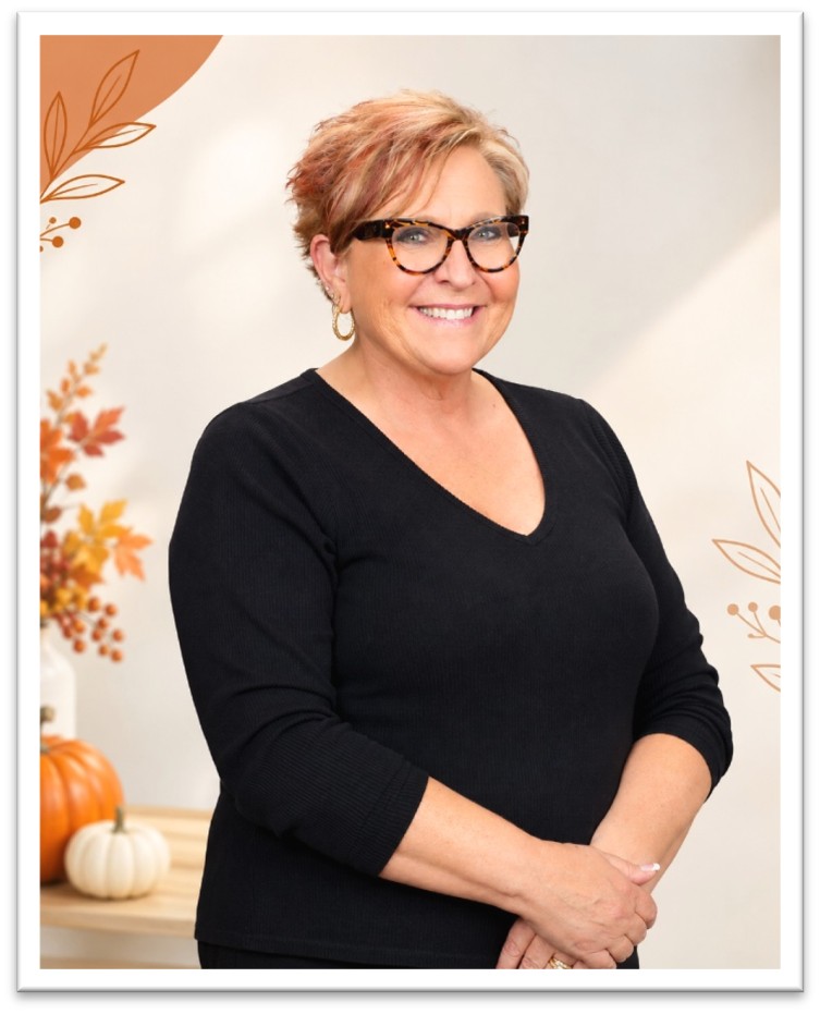 A smiling woman with short hair and glasses wearing a black shirt, framed by autumn-themed illustrations and pumpkins.