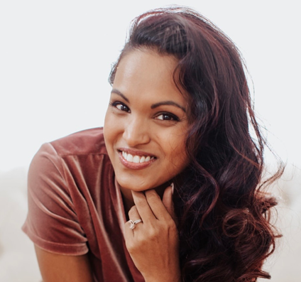 A smiling woman resting her chin on her hand.